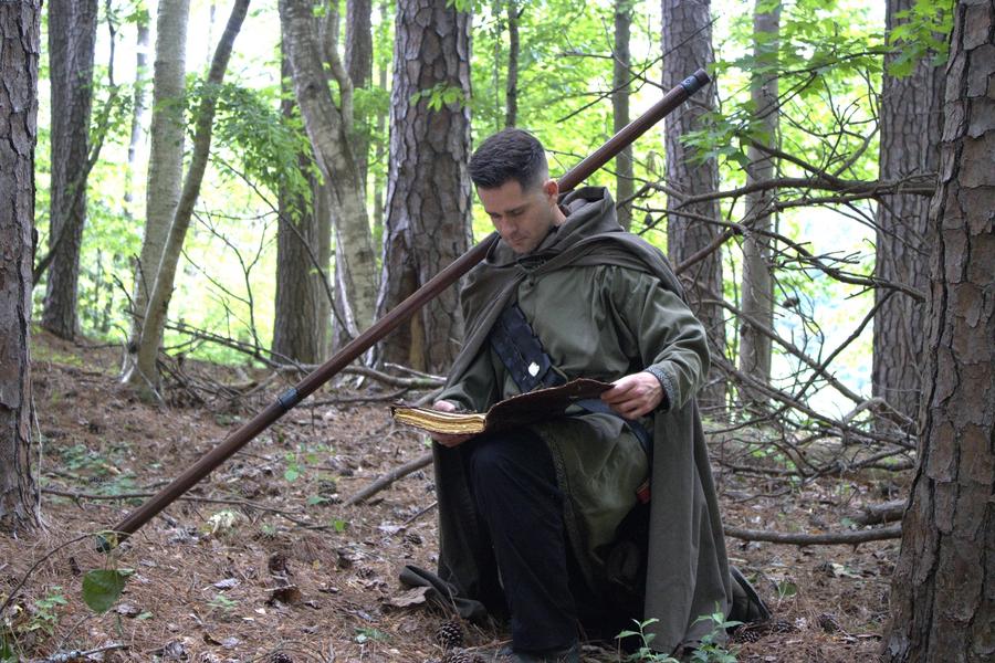 A cloaked figure studying ancient texts